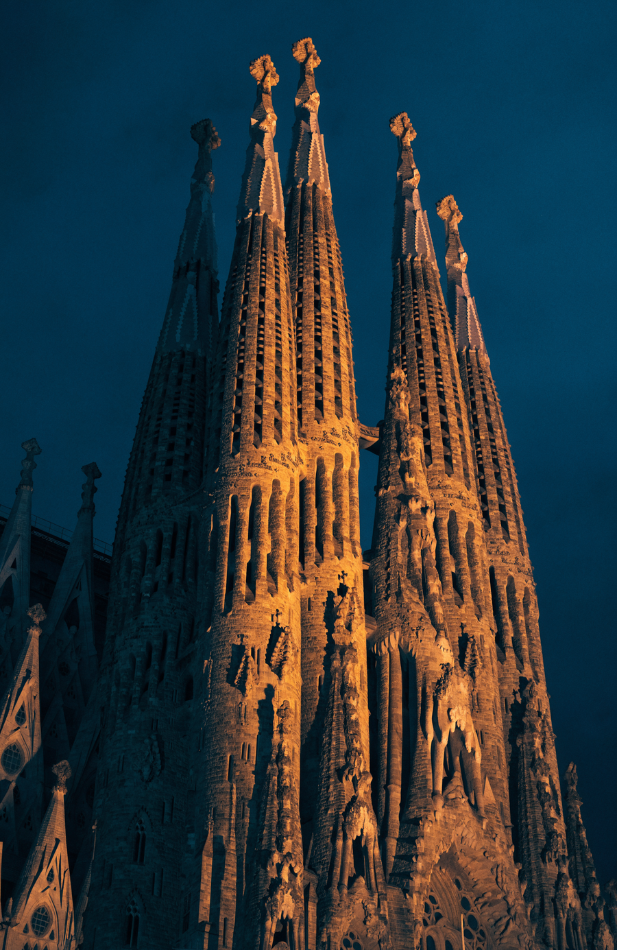Gaudí's spires climb into the Barcelona night, lit warm gold from the ground up