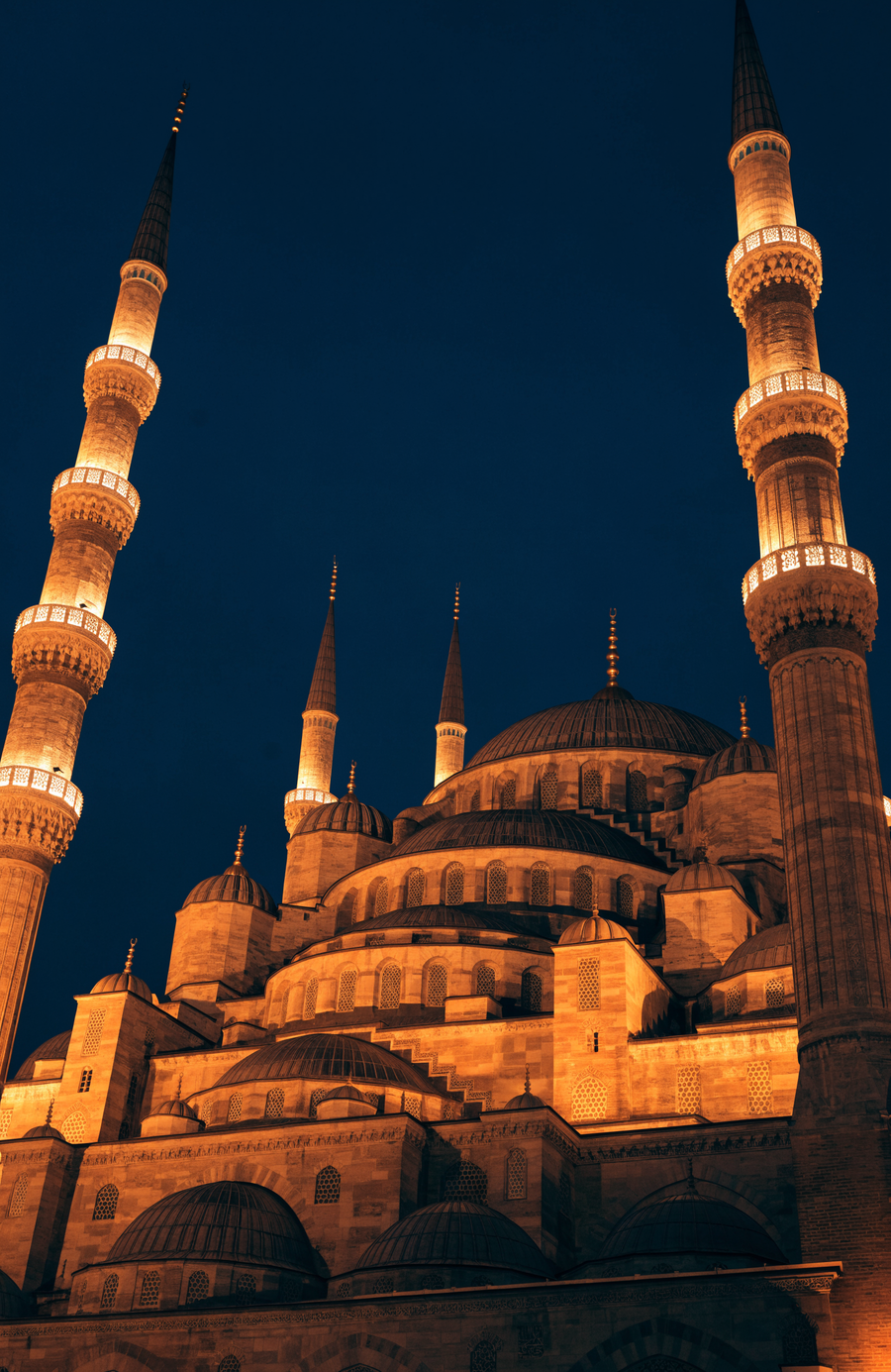 The domes and minarets of the Blue Mosque stand lit in warm gold against the Istanbul night