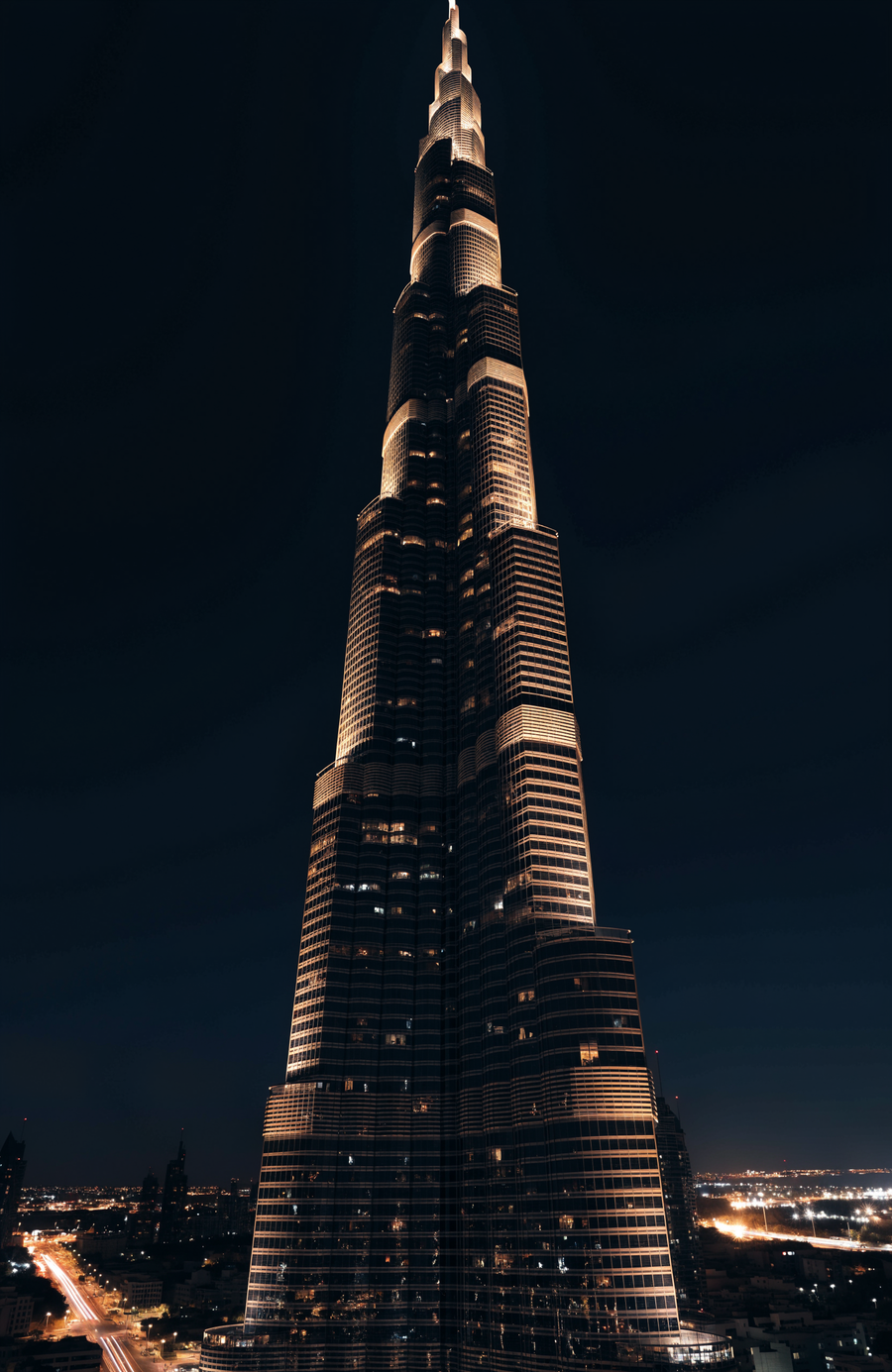 The Burj Khalifa rises through the night in warm gold, the lights of Dubai glittering far below
