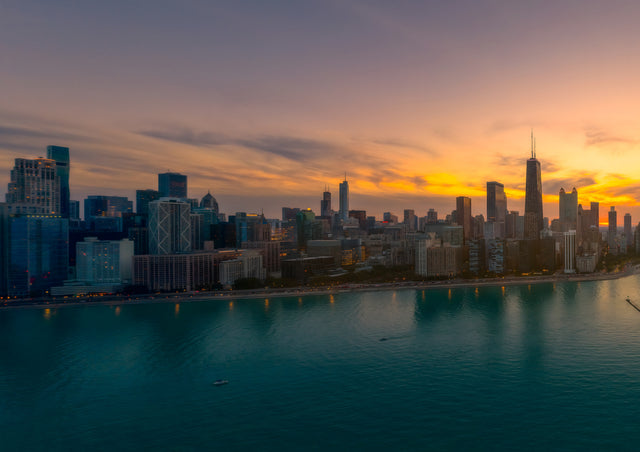 The Chicago skyline burns orange along the edge of Lake Michigan as the sun goes down behind the towers