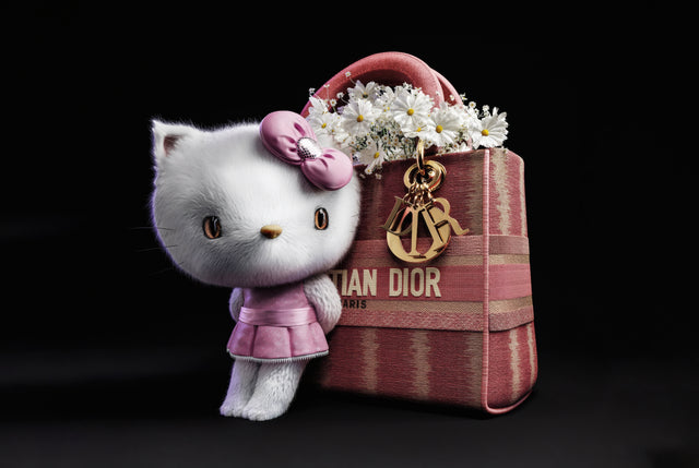 Hello Kitty – Designer Icon - hello Kitty stood beside a monogrammed handbag and a charm on a gold chain, shot against black, on a metal wall art plate