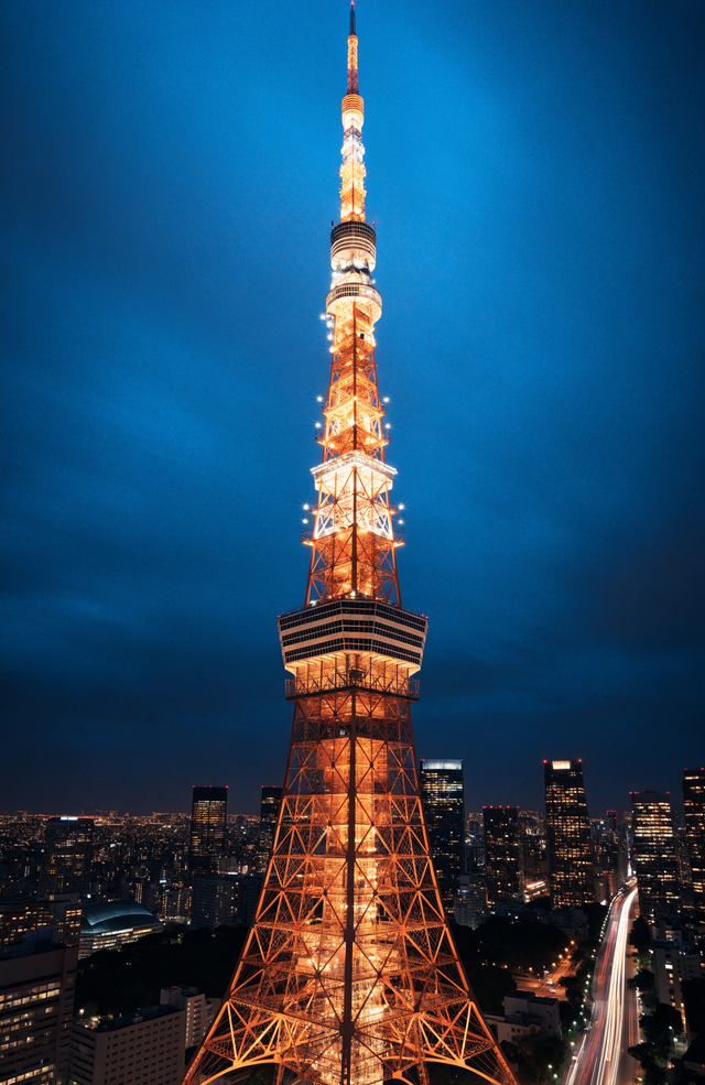 Tokyo Tower burns orange and gold above the city, its lattice sharp against the deep blue night