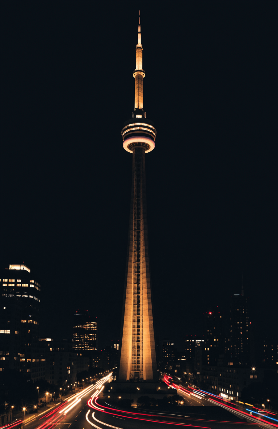 The CN Tower glows above the Toronto skyline, the lake holding its reflection